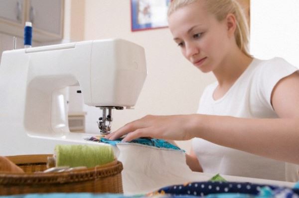 Young woman sits making patchwork at sewing machine --- Image by © Vladimir Godnik/moodboard/Corbis
